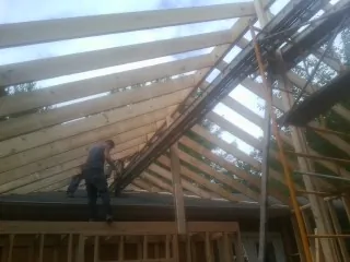 Rafters going up over a new addition with a worker on the wall in New Haven