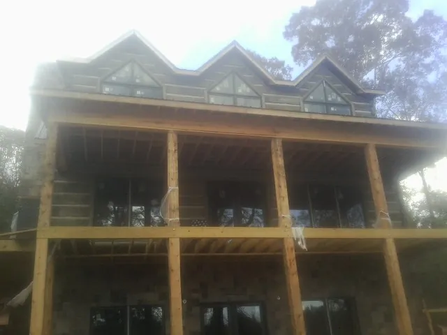 Dormers and porch framing on a large log home under construction — Roof Coating work by our crew in New Haven