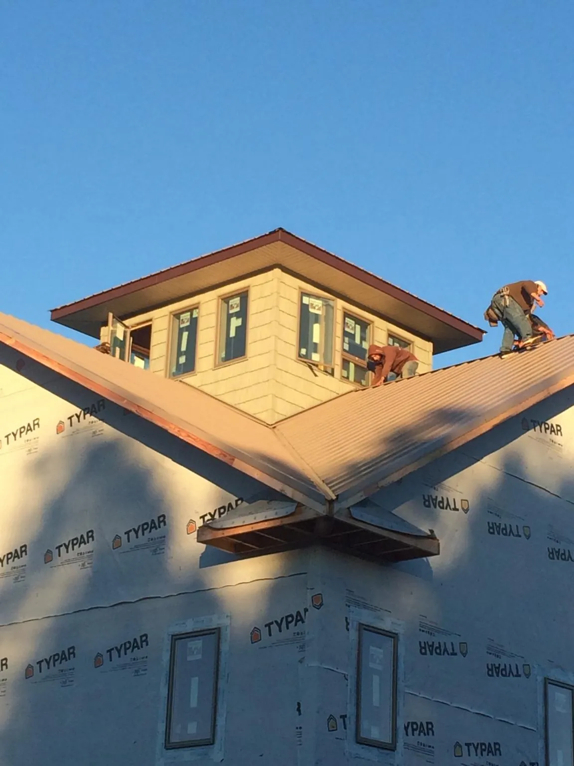 Roofers working around a rooftop cupola on a new metal roof at sunset — Roof Waterproofing in New Haven by Roofing Brothers